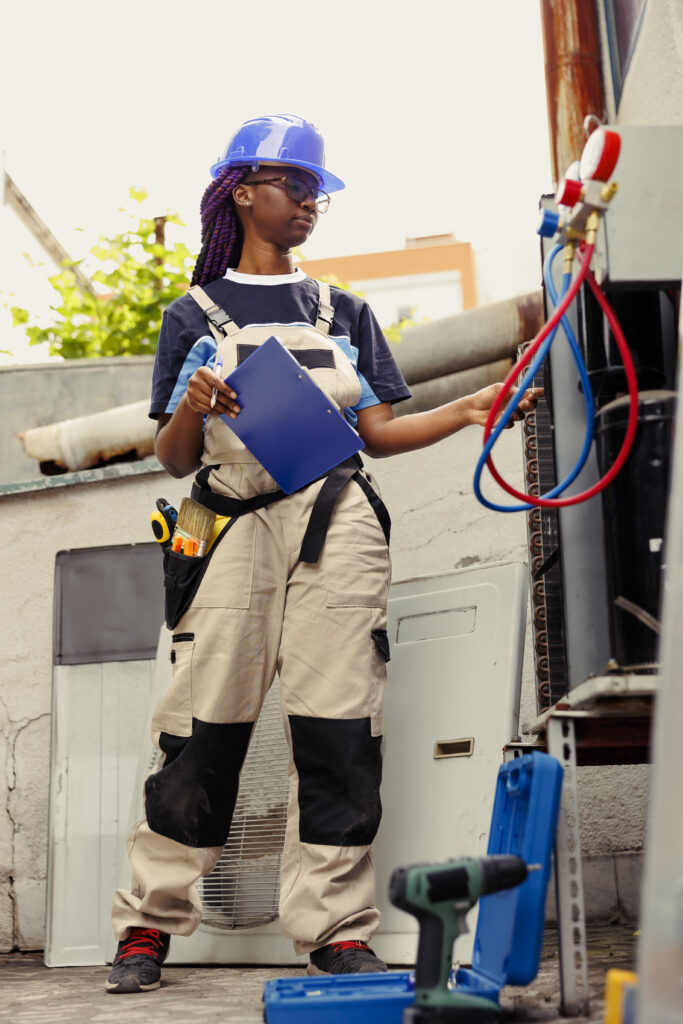 Repairman optimizes HVAC system efficacy Adept repairman commissioned to optimize HVAC system efficacy, ensuring it operates at maximum capability. Proficient worker doing condenser unit investigation, imputing data on laptop